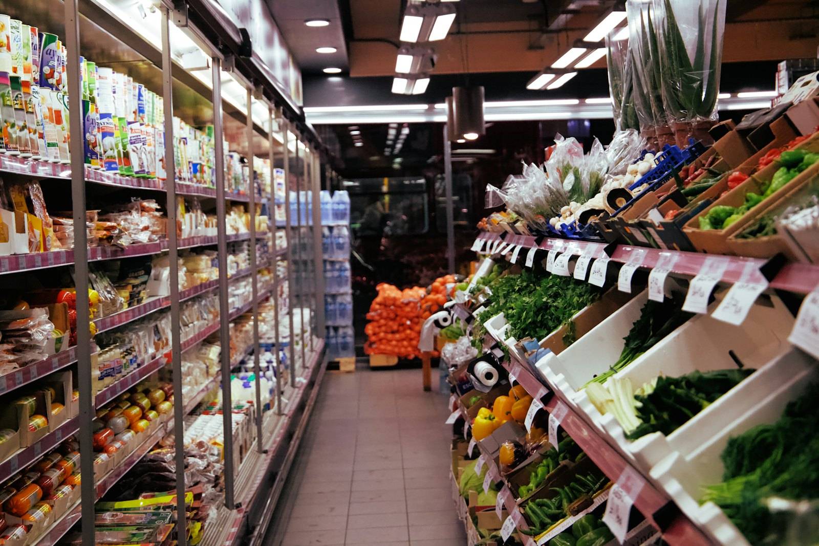 野菜と日用品が並ぶ、細い通路の売り場